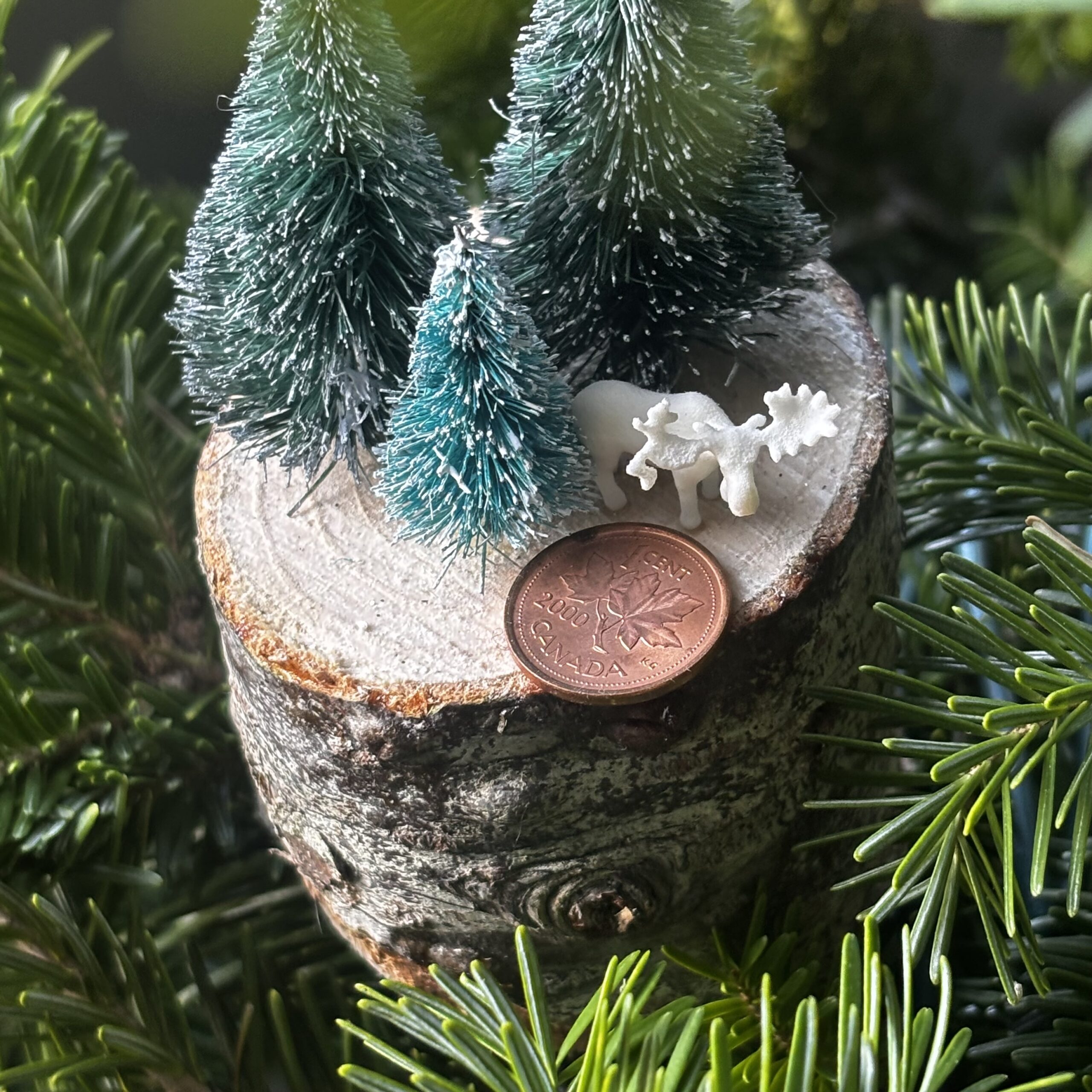 High-resolution SLS 3D printed miniature moose shown next to a penny for scale, demonstrating precision additive manufacturing capabilities in Canada
